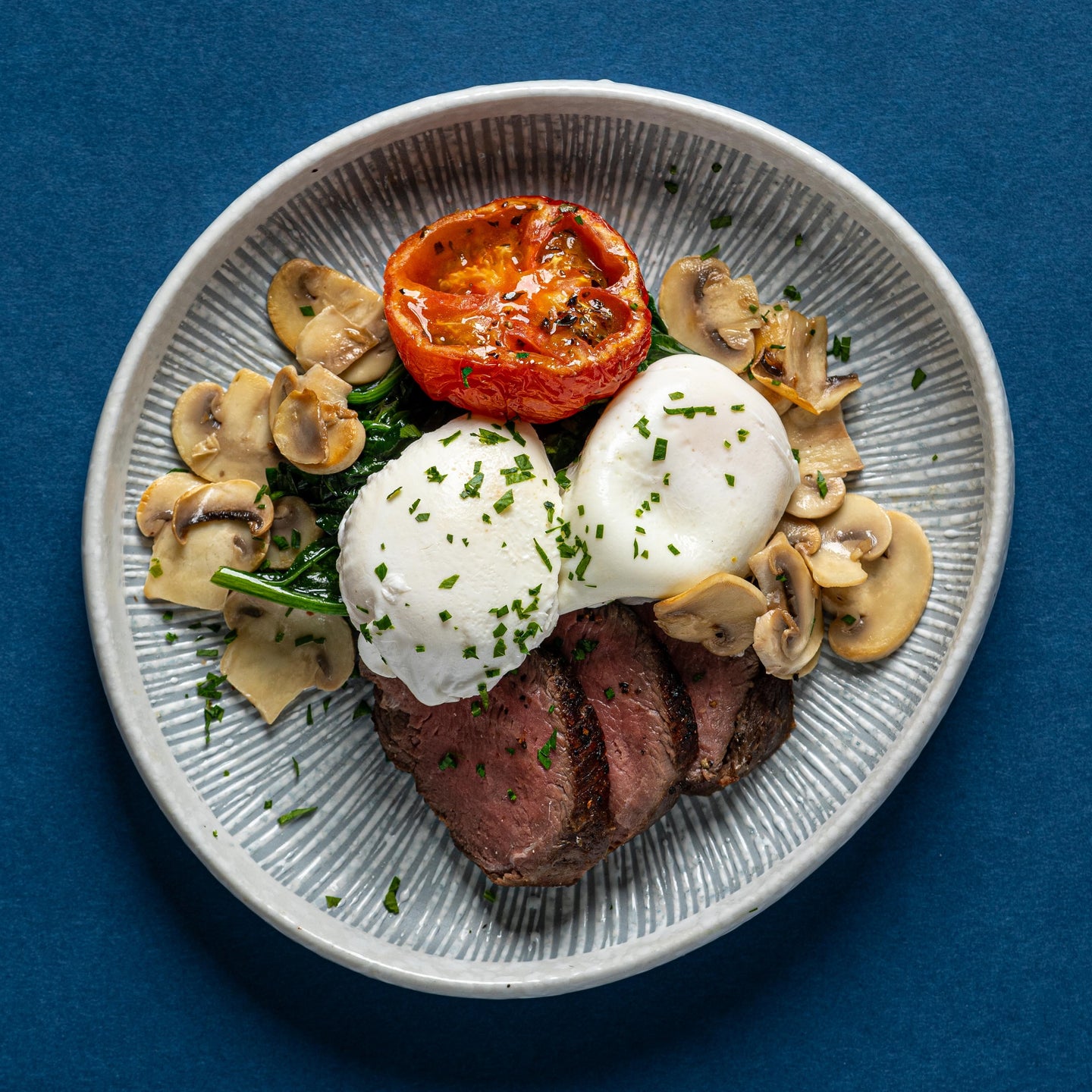 Poached Eggs and Sliced Beef Tenderloin with Spinach, Mushrooms, Roasted Tomato & Chimichurri